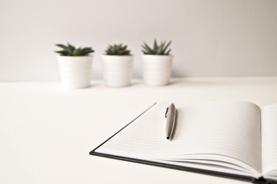 A minimal desk with notebook and pen